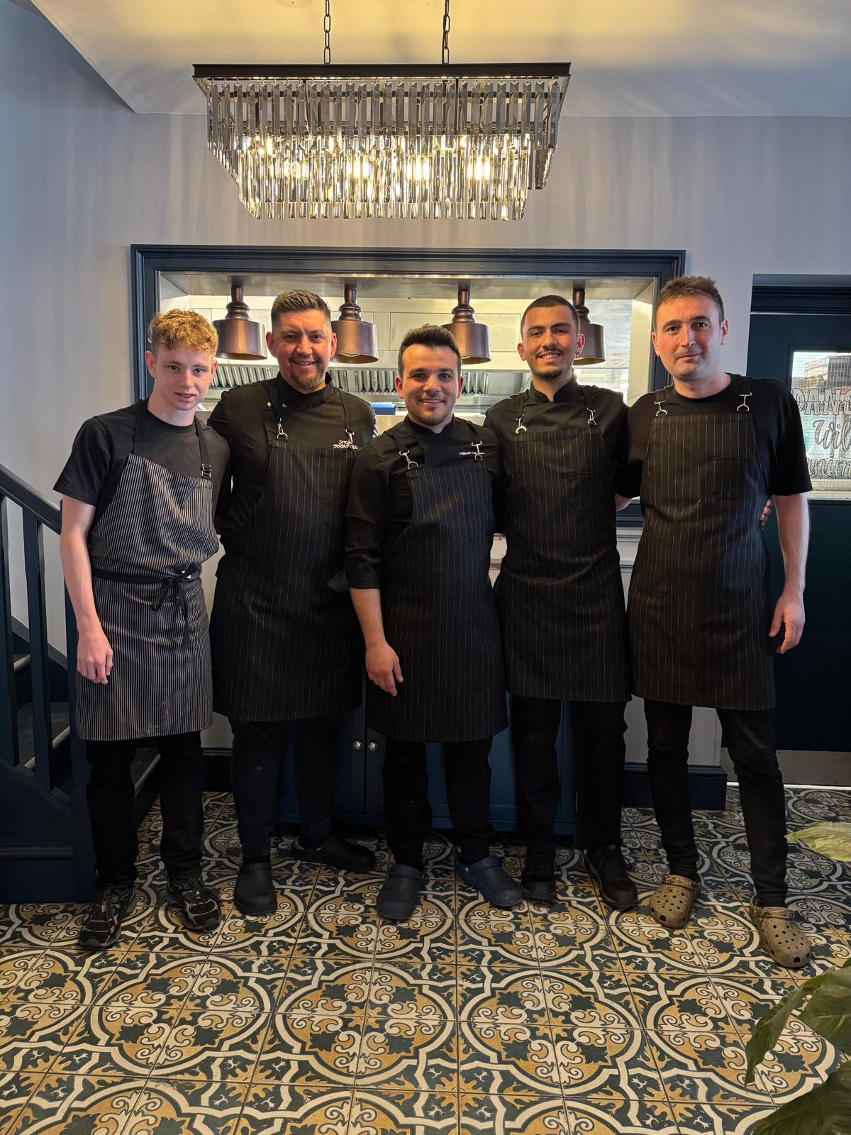 Mikail with a team of chefs in matching aprons