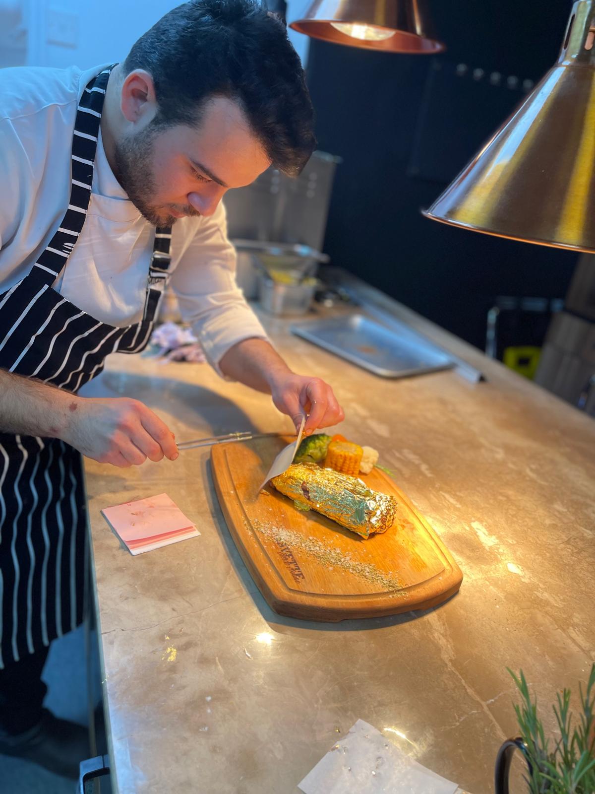 Steak wrapped in gold leaf on a wooden board