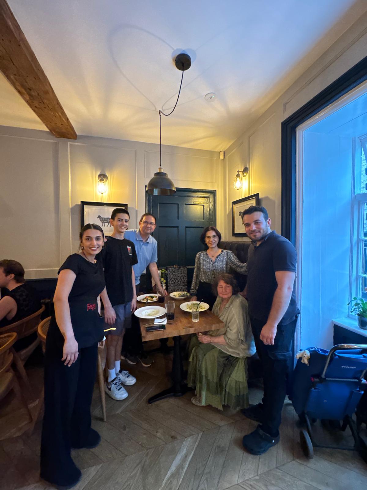Mikail with a family of guests around their dinner table